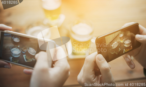 Image of close up of hands with smartphone picturing beer