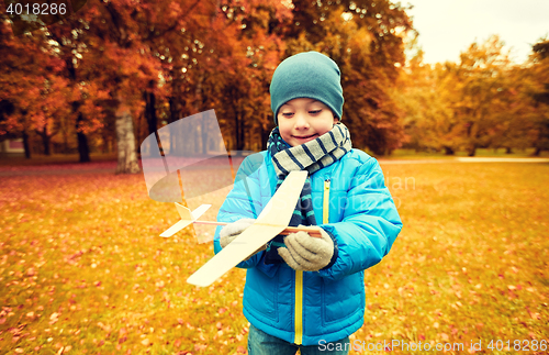 Image of happy little boy playing with toy plane outdoors