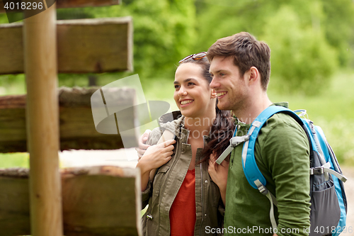 Image of smiling couple at signpost with backpacks hiking