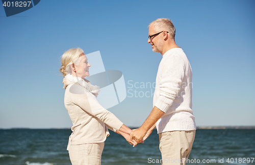 Image of happy senior couple holding hands summer beach
