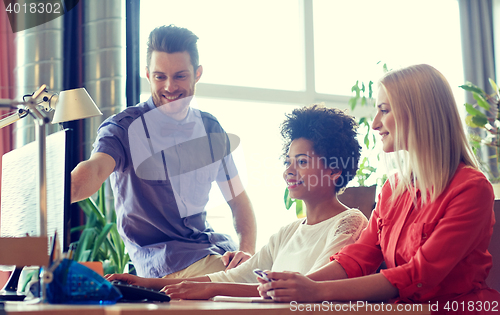 Image of happy creative team with computer in office