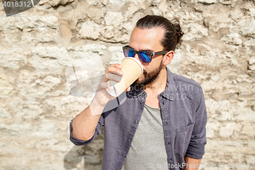 Image of man drinking coffee from paper cup on street