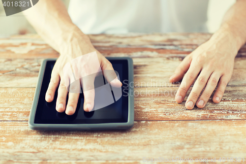 Image of close up of male hands with tablet pc on table