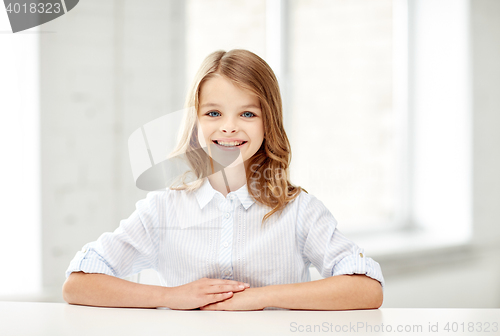 Image of happy smiling school girl sitting at table