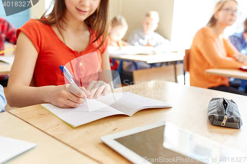 Image of close up of student writing to notebook at school