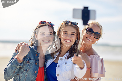 Image of group of smiling women taking selfie on beach