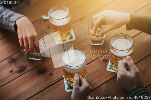 Image of close up of hands with beer mugs at bar or pub