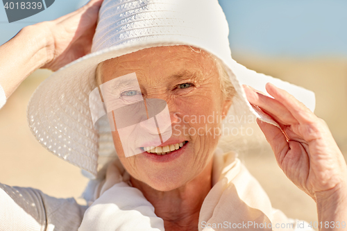Image of happy senior woman in sun hat on summer beach