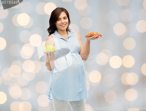 Image of happy pregnant woman with apple and croissant