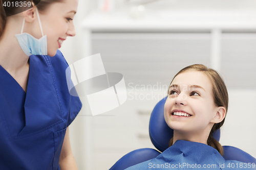 Image of happy female dentist with patient girl at clinic