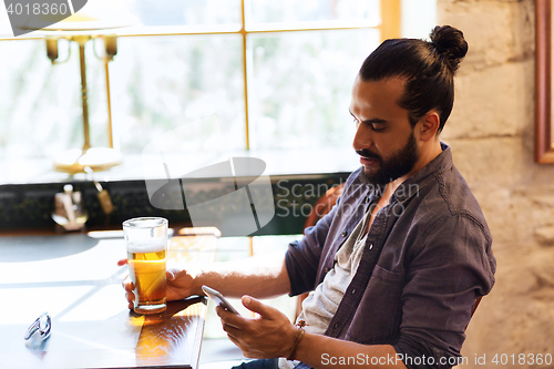 Image of man with smartphone drinking beer at bar or pub