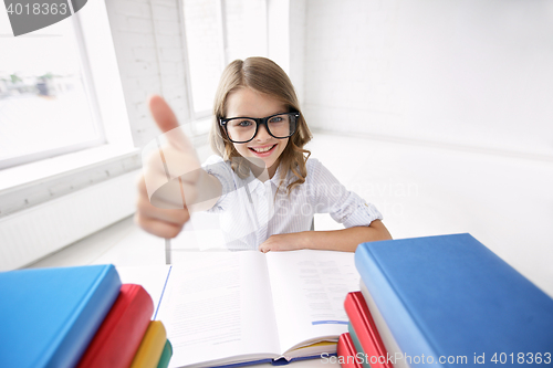 Image of happy school girl with books showing thumbs up