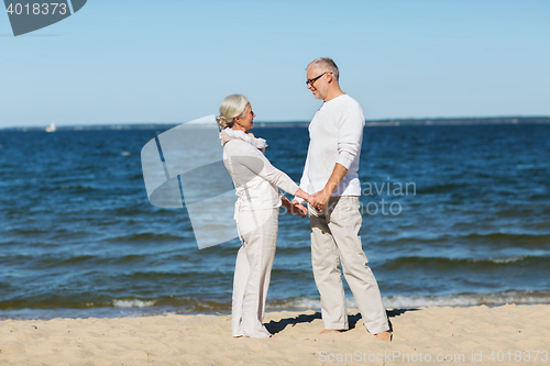 Image of happy senior couple holding hands on summer beach