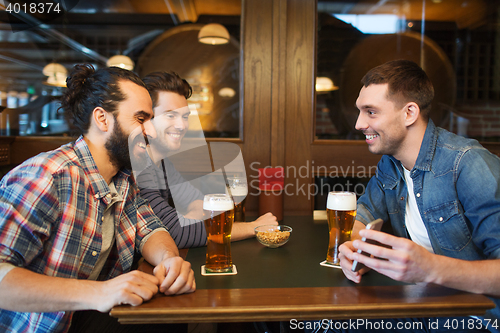 Image of male friends with smartphone drinking beer at bar