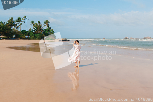 Image of Woman legs walking on the beach sand