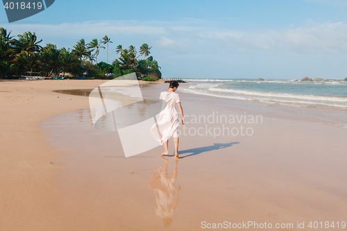 Image of Woman legs walking on the beach sand