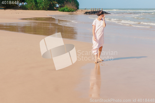 Image of Woman walking on the beach sand