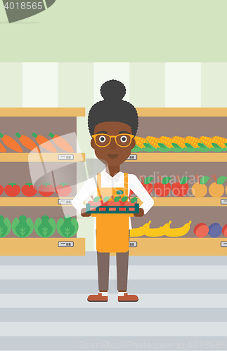 Image of Supermarket worker with box full of apples.