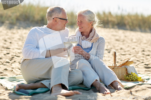 Image of happy senior couple having picnic on summer beach