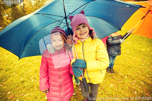 Image of happy children with umbrella in autumn park