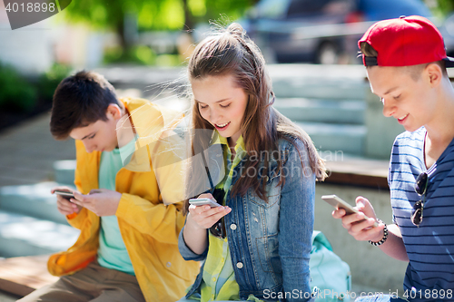 Image of happy teenage friends with smartphones outdoors