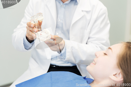 Image of close up of dentist showing teeth maquette to girl