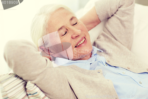 Image of happy senior woman resting on sofa at home