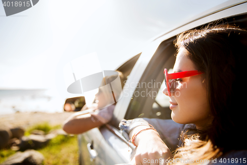 Image of happy teenage girls or women in car at seaside