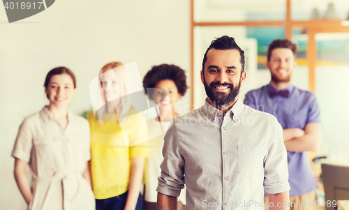 Image of happy young man over creative team in office