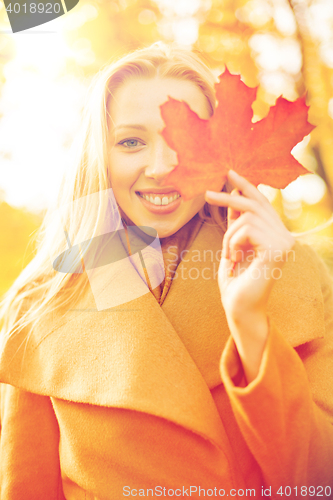 Image of woman with red marple leaf in the autumn park