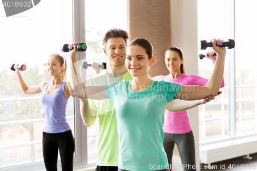 Image of group of smiling people exercising with dumbbells