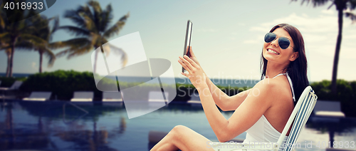 Image of smiling woman with tablet pc sunbathing on beach