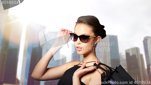 Image of happy woman in black sunglasses with shopping bags