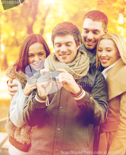 Image of group of friends with photo camera in autumn park