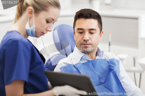 Image of female dentist with tablet pc and male patient