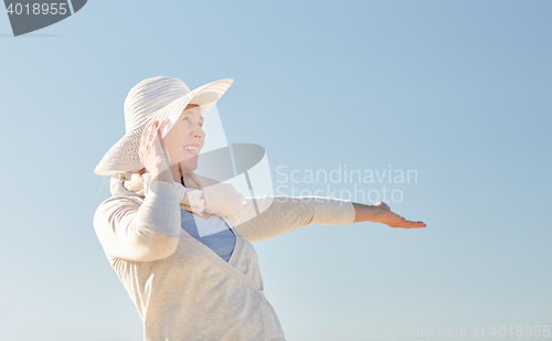 Image of happy senior woman in sun hat over blue sky