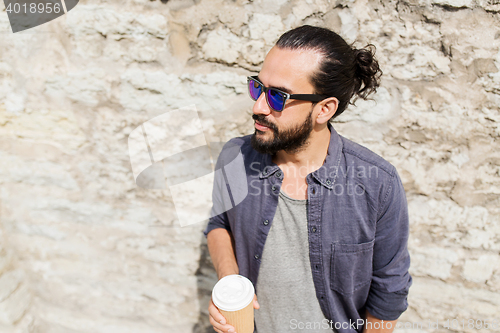 Image of man drinking coffee from paper cup on street