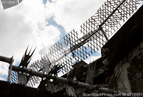 Image of close up of fence with barbed wire and mesh