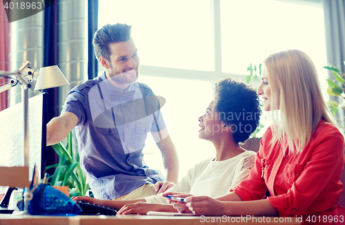 Image of happy creative team with computer in office