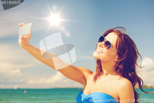 Image of happy woman with phone on the beach