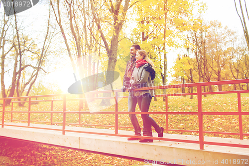 Image of smiling couple hugging on bridge in autumn park