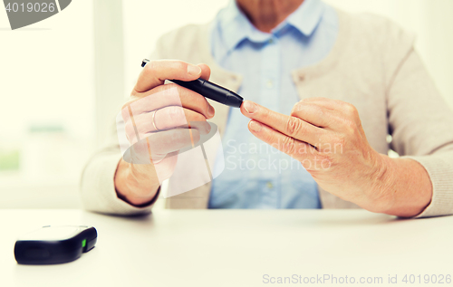 Image of senior woman with glucometer checking blood sugar