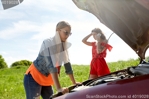 Image of women with open hood of broken car at countryside