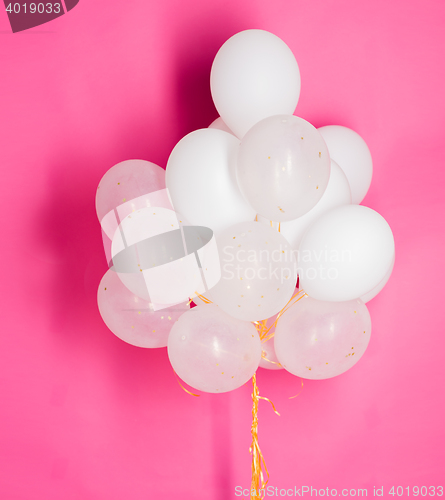 Image of close up of white helium balloons over pink