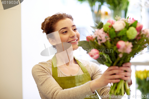 Image of smiling florist woman making bunch at flower shop