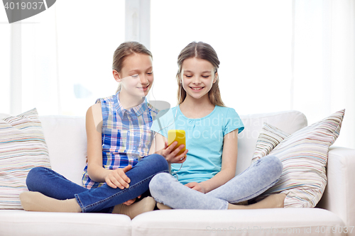 Image of happy girls with smartphone sitting on sofa