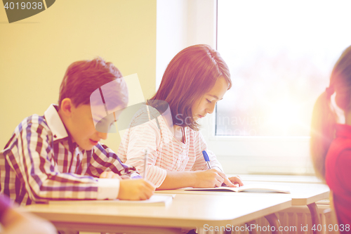 Image of group of school kids writing test in classroom