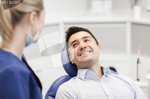Image of female dentist with happy male patient at clinic