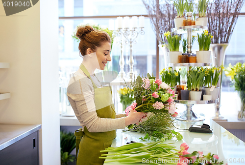 Image of smiling florist woman making bunch at flower shop