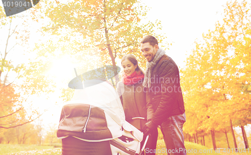 Image of smiling couple with baby pram in autumn park